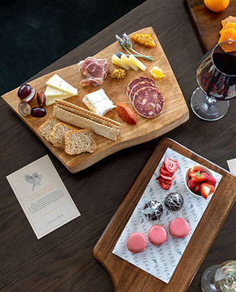 charcuterie board, fruit board, dessert board, and glass of wine on a table