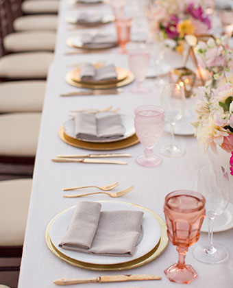 Wedding table setting with plates, candles, and a tall floral centerpiece with draping crystals